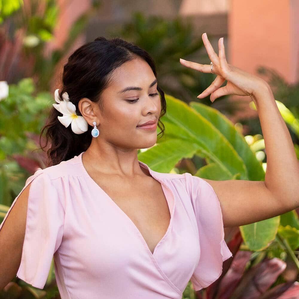woman wearing a plumeria flower on right ear with a larimar earrings, posing on traditional Cambodian dance