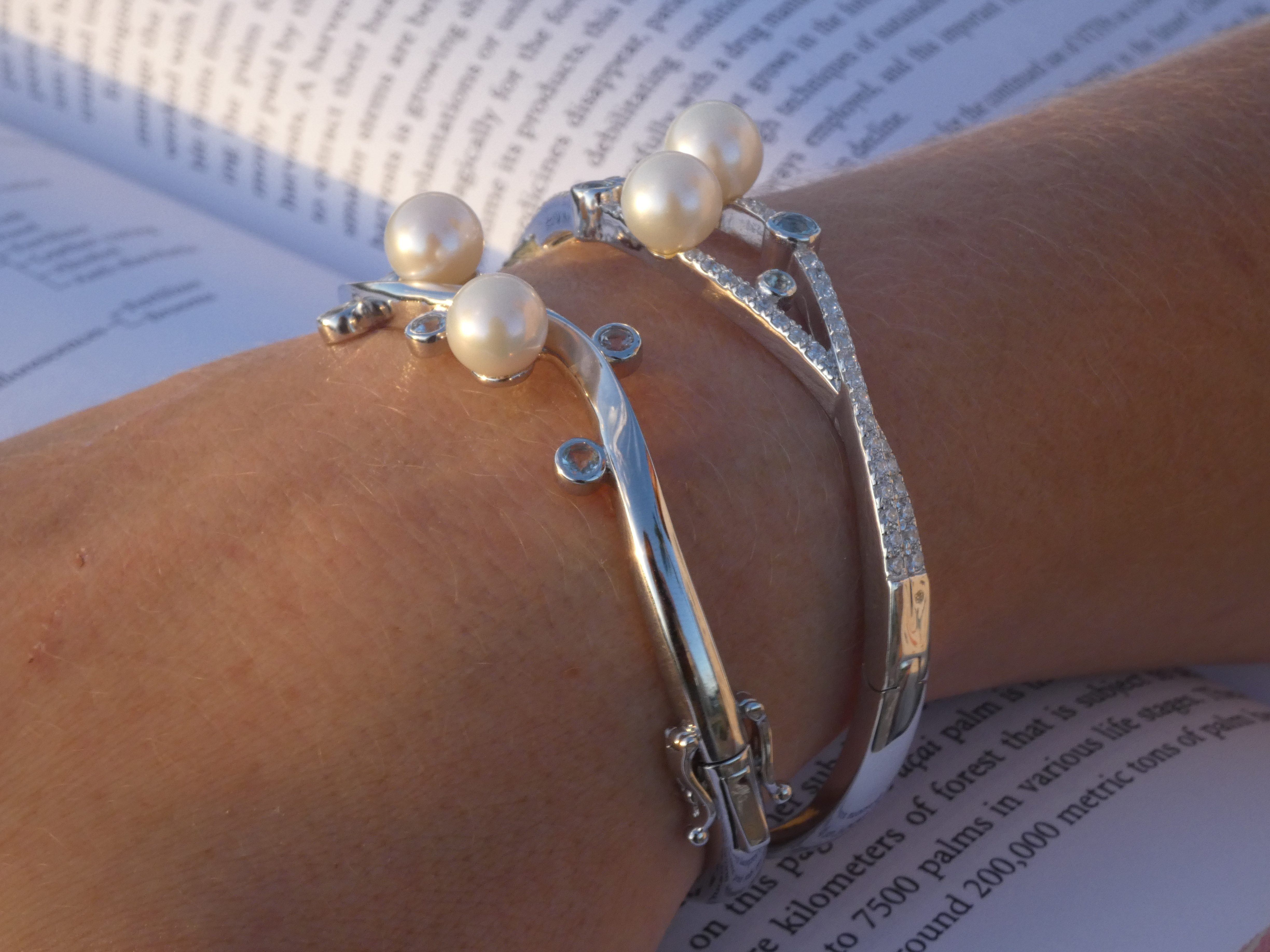 The photo shows two silver bracelets featuring pearls. 