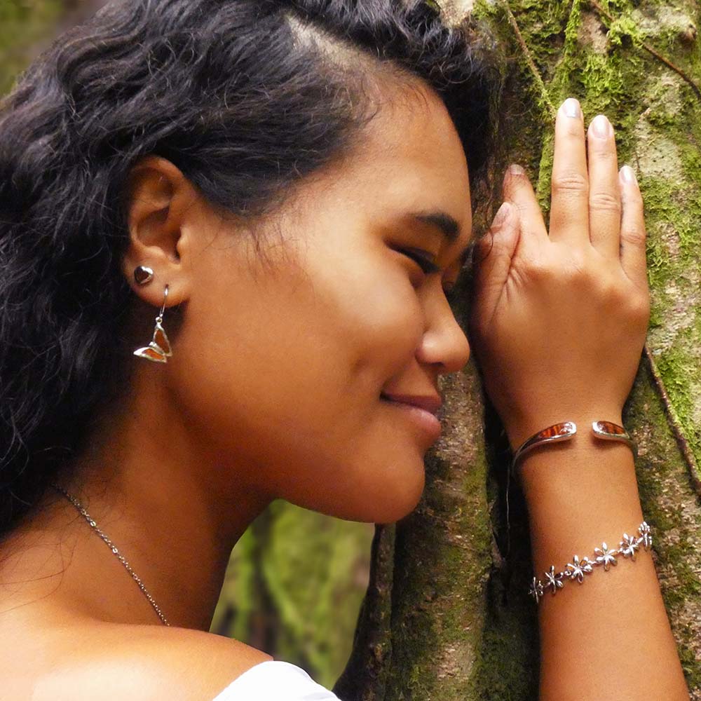 koa wood collection jewelry set featuring heart stud earring and butterfly hook earrings paired up with koa wood cuff bangle and jasmine flower bracelet worn by a model