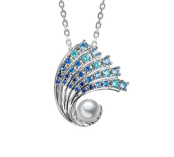 In this photo there is a small white gold ombre wave pendant with gradient blue aquamarine gemstones and one white south sea pearl.