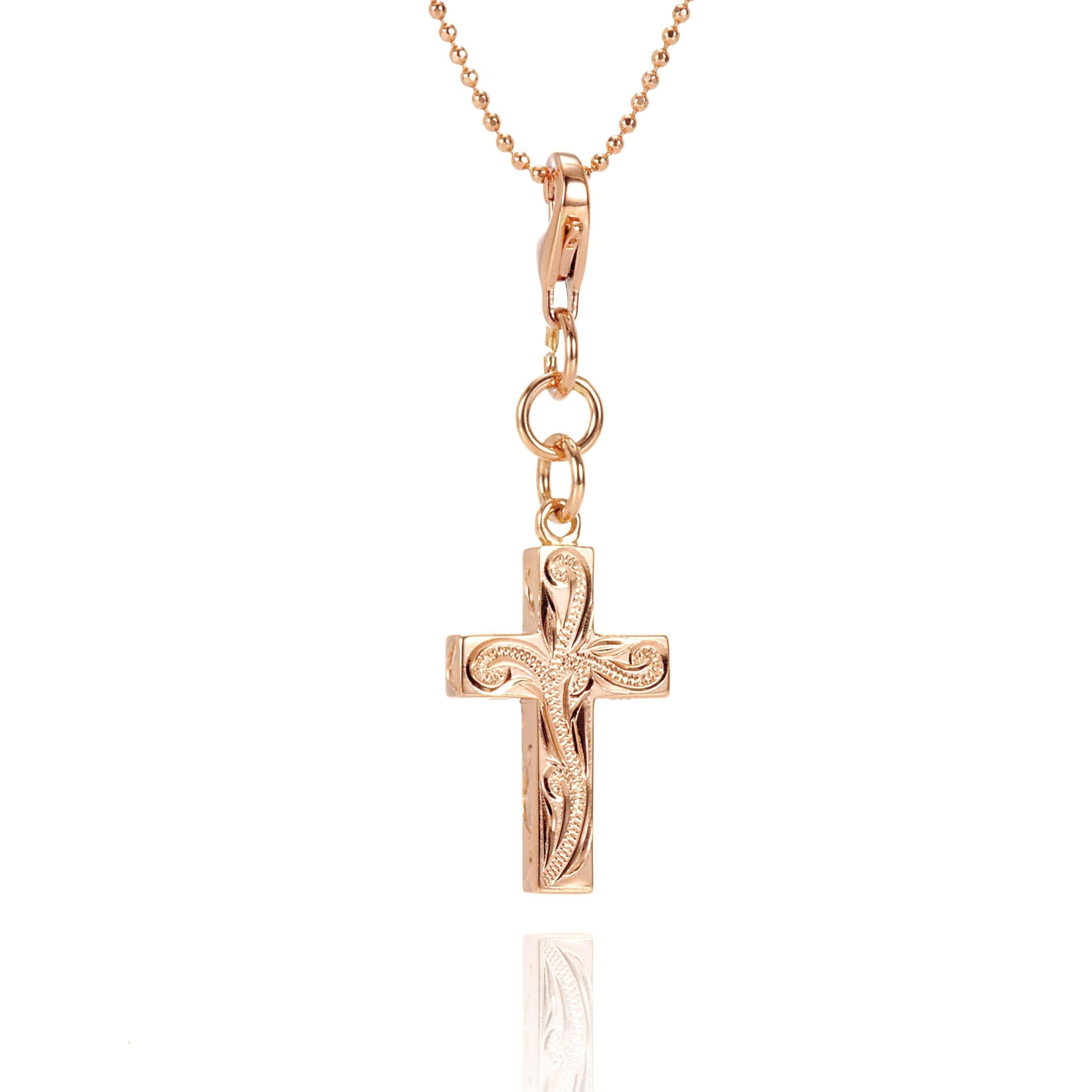 The picture shows a 14K yellow gold cross charm with hand-engraved detailing.