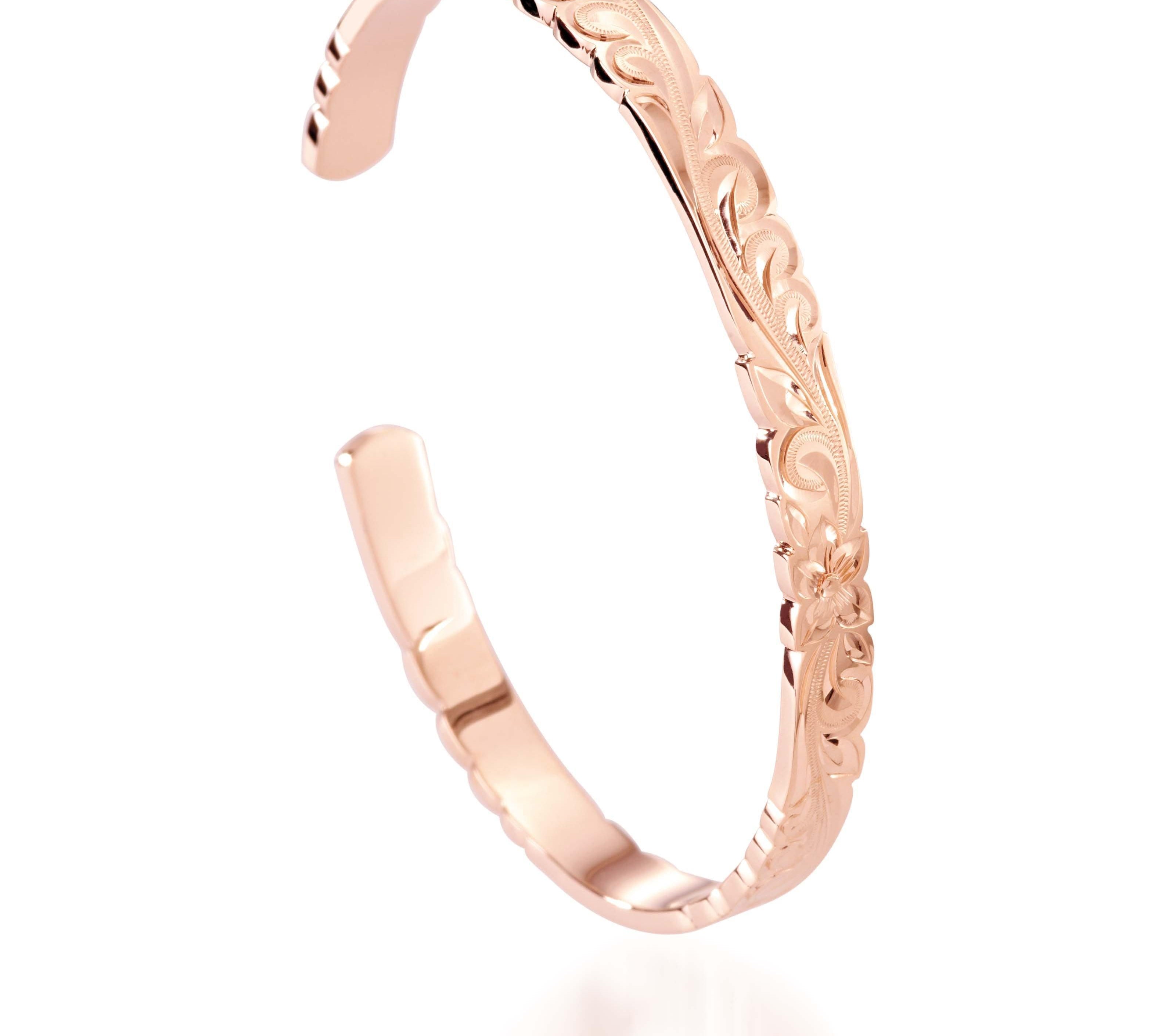 The picture shows a 14K rose gold cut-out bangle with plumeria engraving.