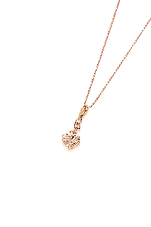 In this photo there is a 14k rose gold heart charm with plumeria engraving.