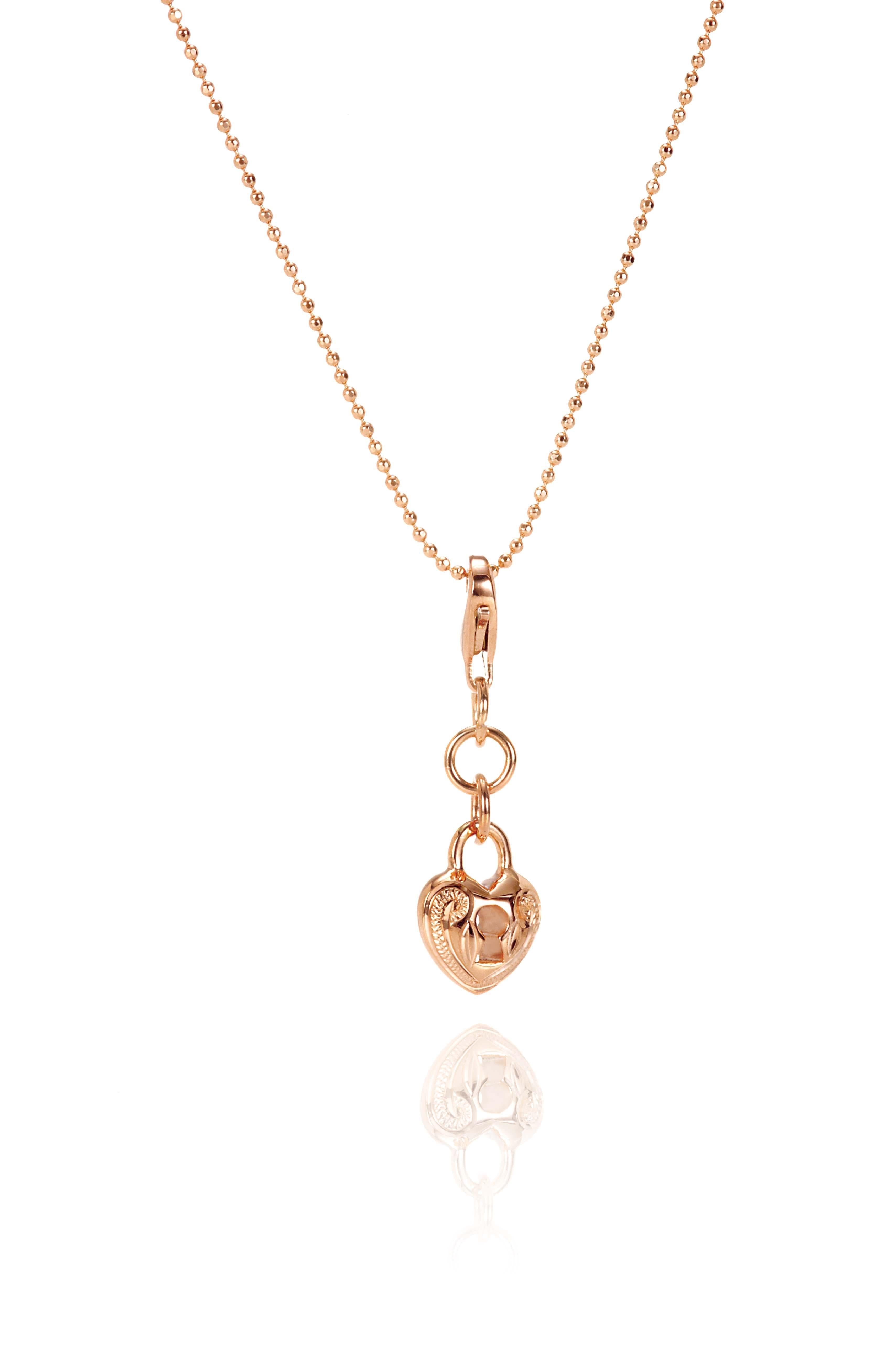 The picture shows a 14K rose gold heart lock charm with hand-engraved detailing.