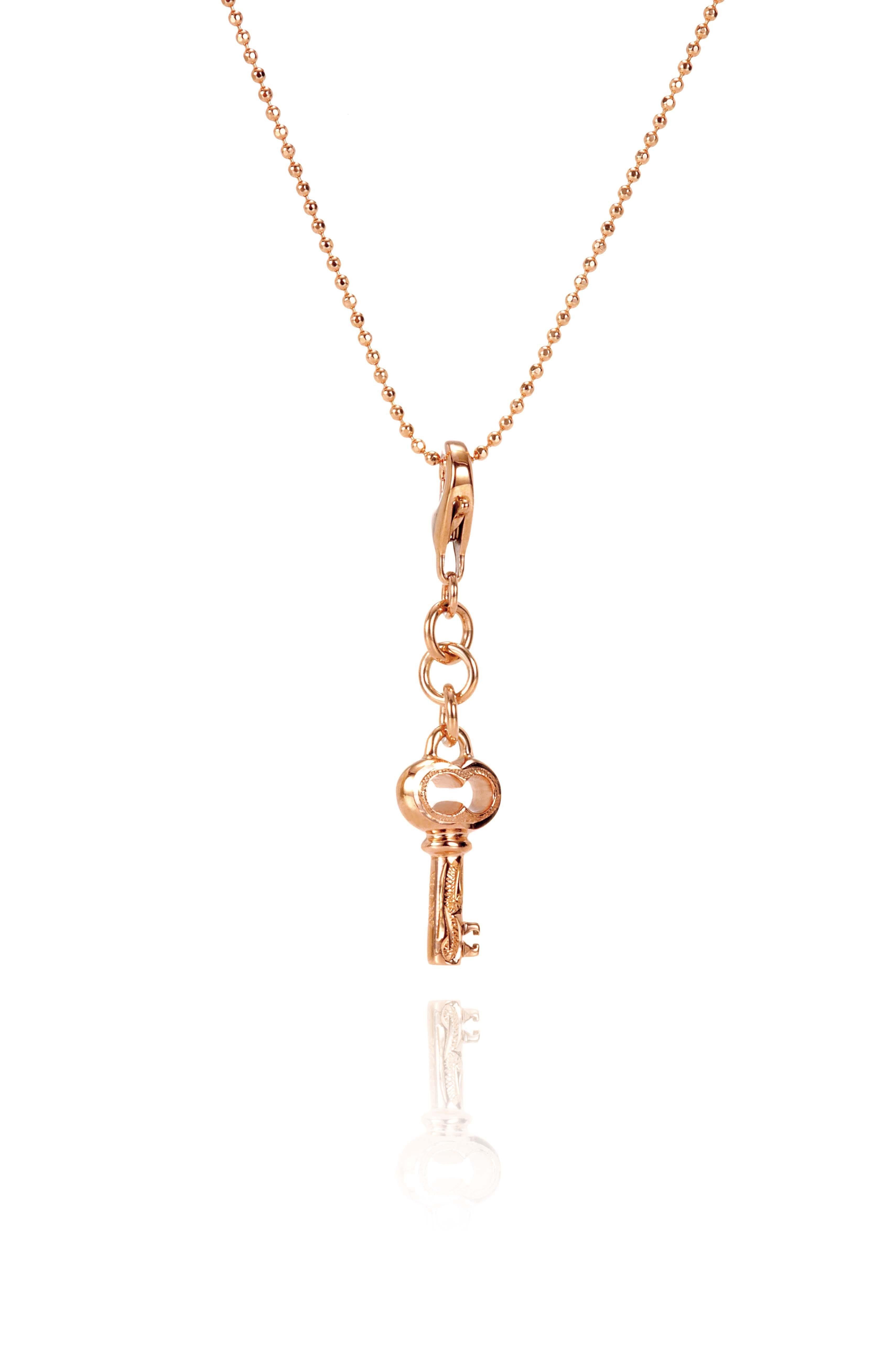 The picture shows a 14K yellow gold key charm with hand-engraved detailing.