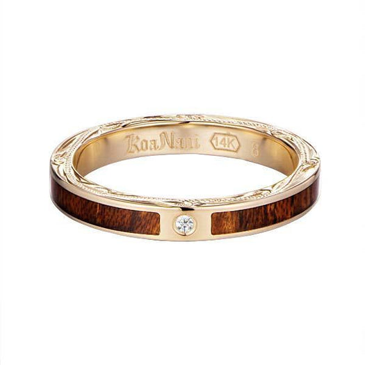 In this photo there is a yellow gold koa wood ring with hand engravings of scrolls and one diamond.