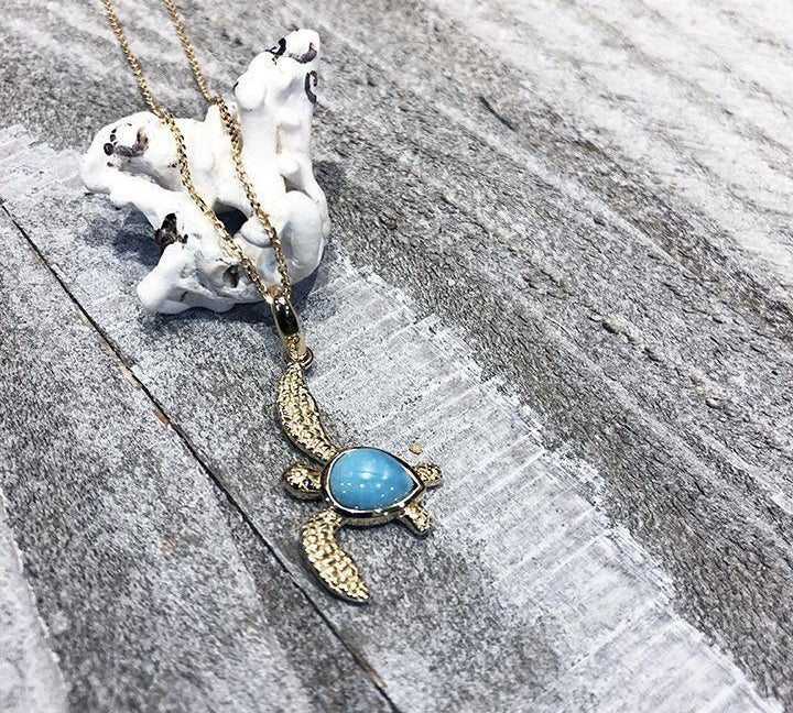 The picture shows a 14K yellow gold sea turtle pendant with a larimar gemstone.