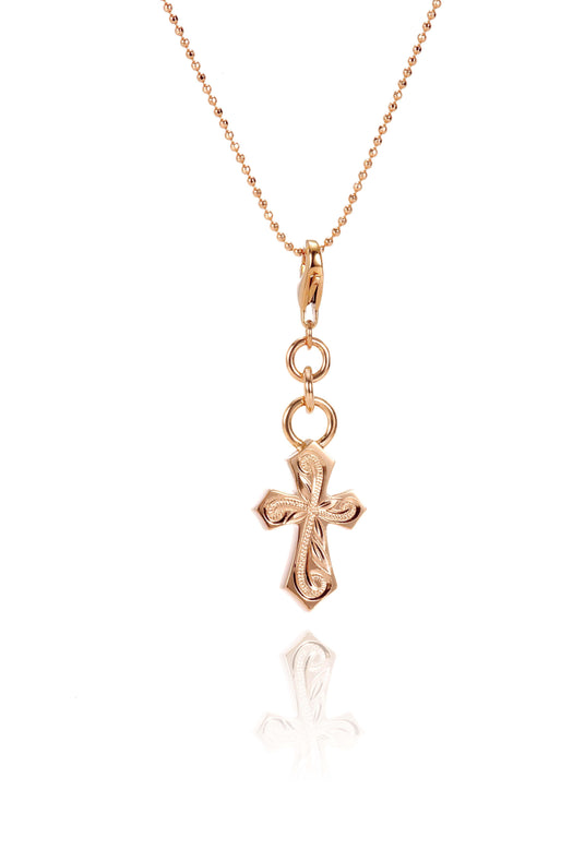 The picture shows a 14K rose gold pointed cross charm with hand-engraved detailing.