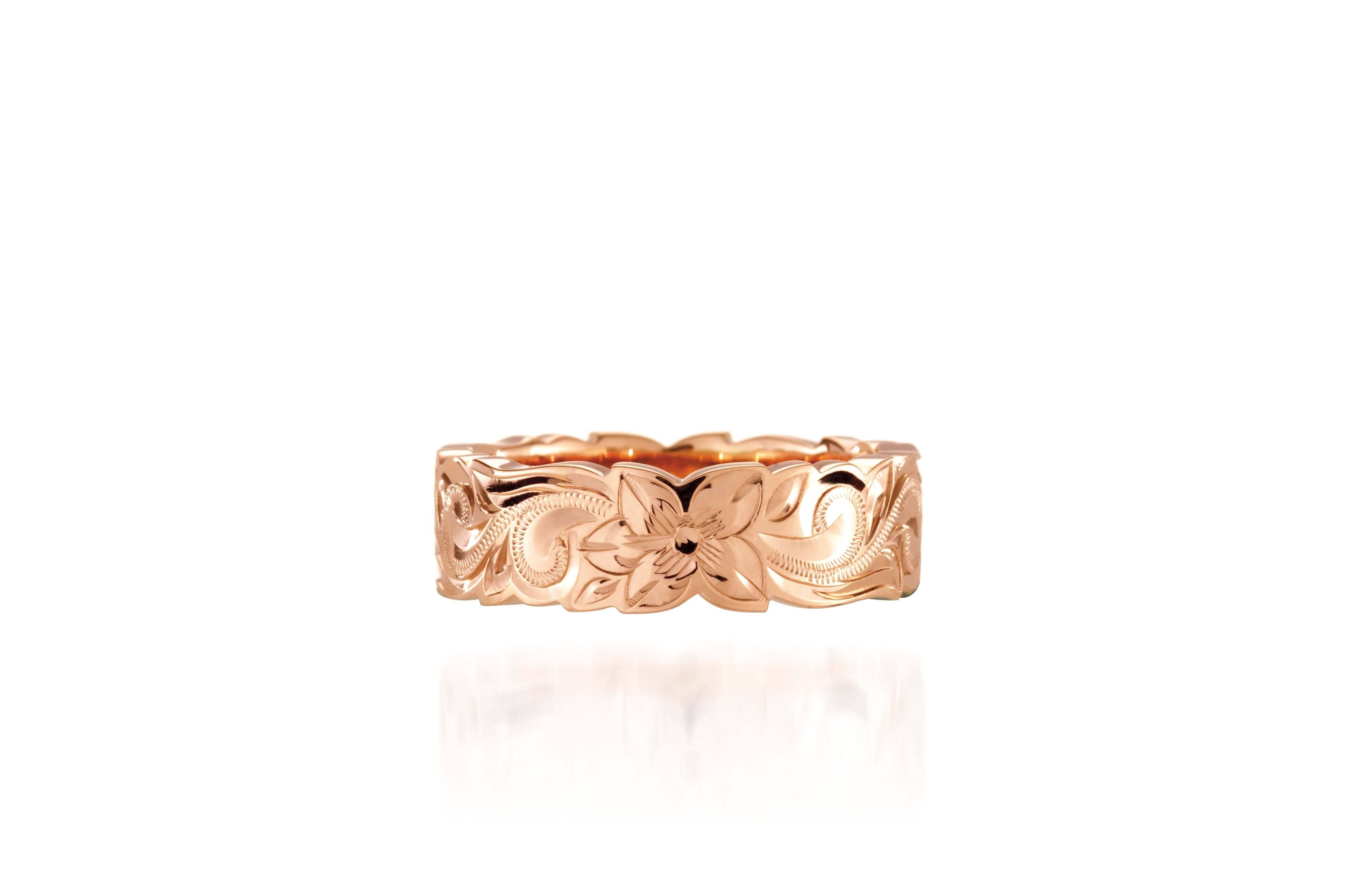 In this picture there is a rose gold cut out ring with hand engravings including flowers and scrolls.