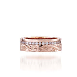 In this photo there is a rose gold ring with diamonds and hand engravings that include a flower and scroll.