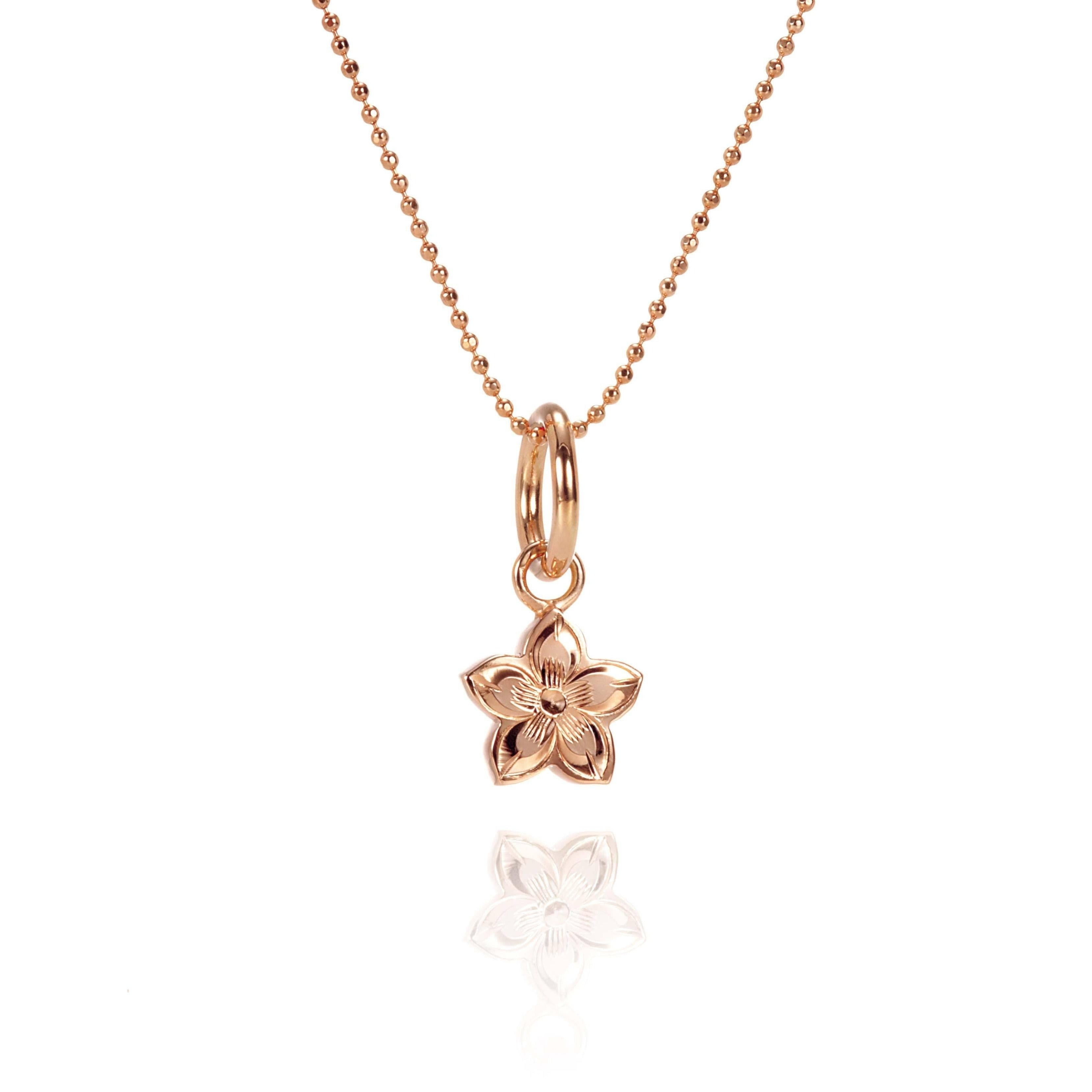 In this photo there is a rose gold plumeria pendant with hand engravings.