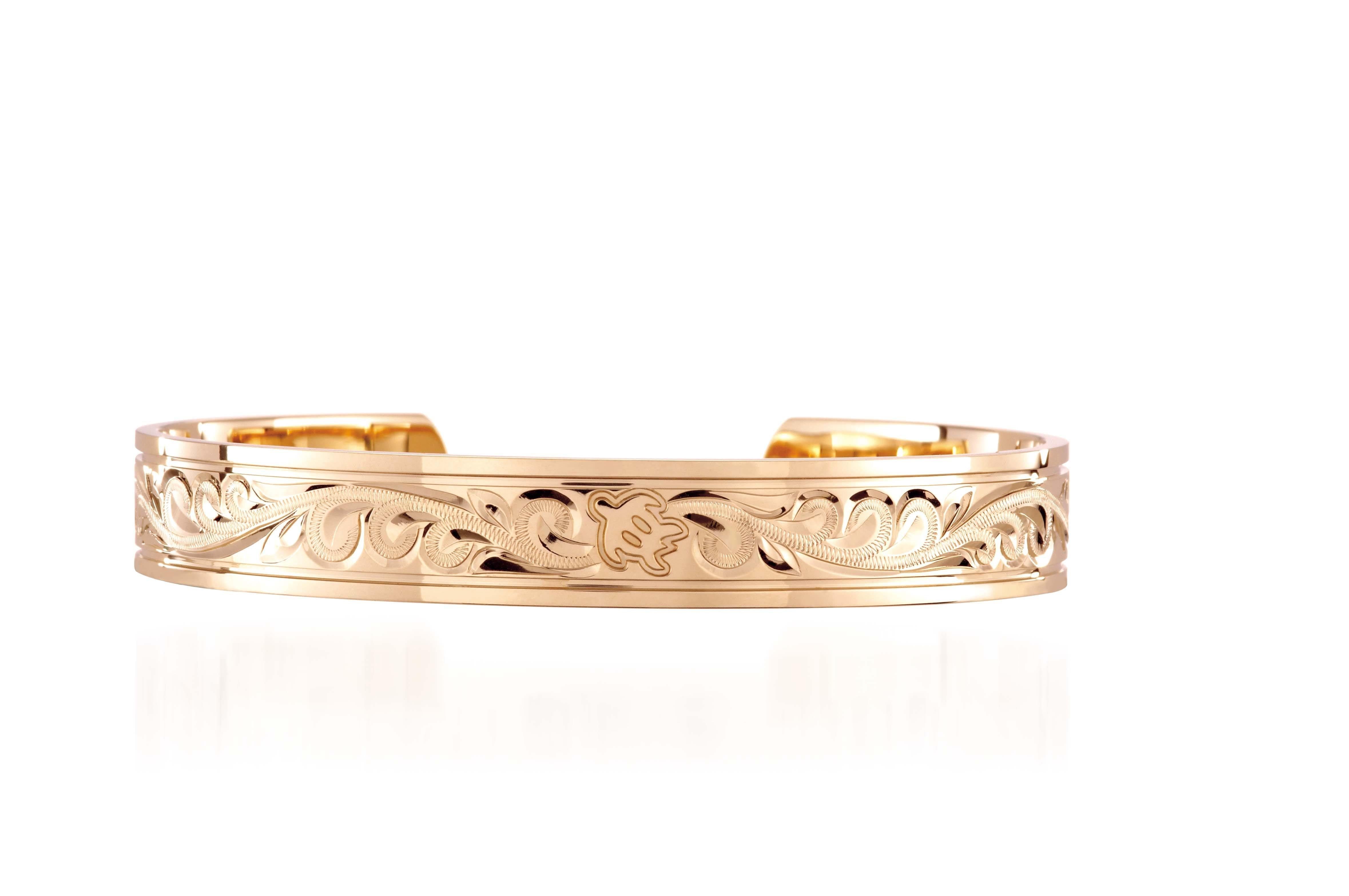 The picture shows a 14K yellow gold royal bangle with sea turtle engravings.