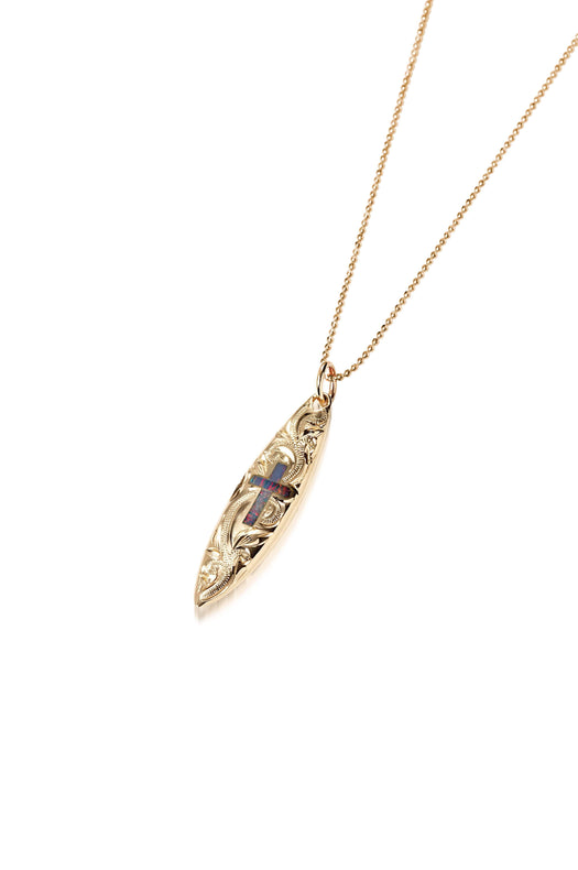 In this photo there is a yellow gold surfboard pendant with an opal cross and hand engravings.