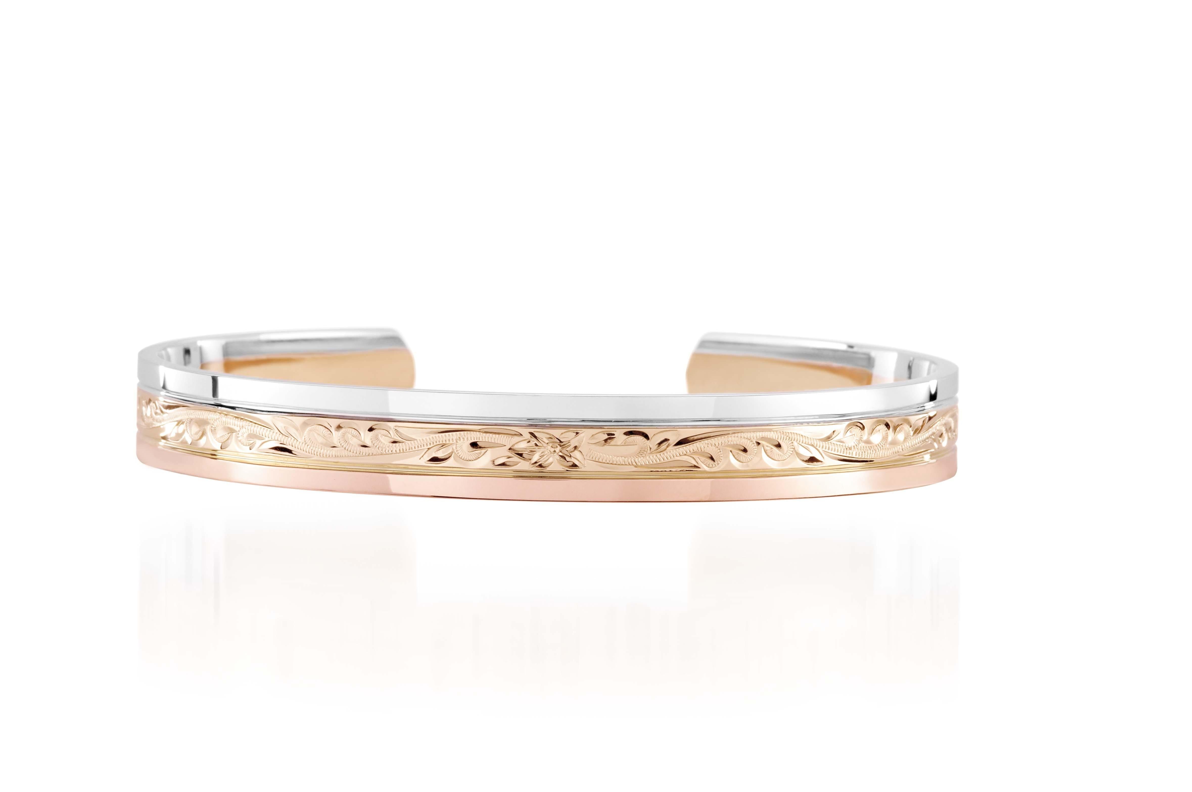 The picture shows a 14K white, yellow, and rose gold tri-color bangle with plumeria engraving.