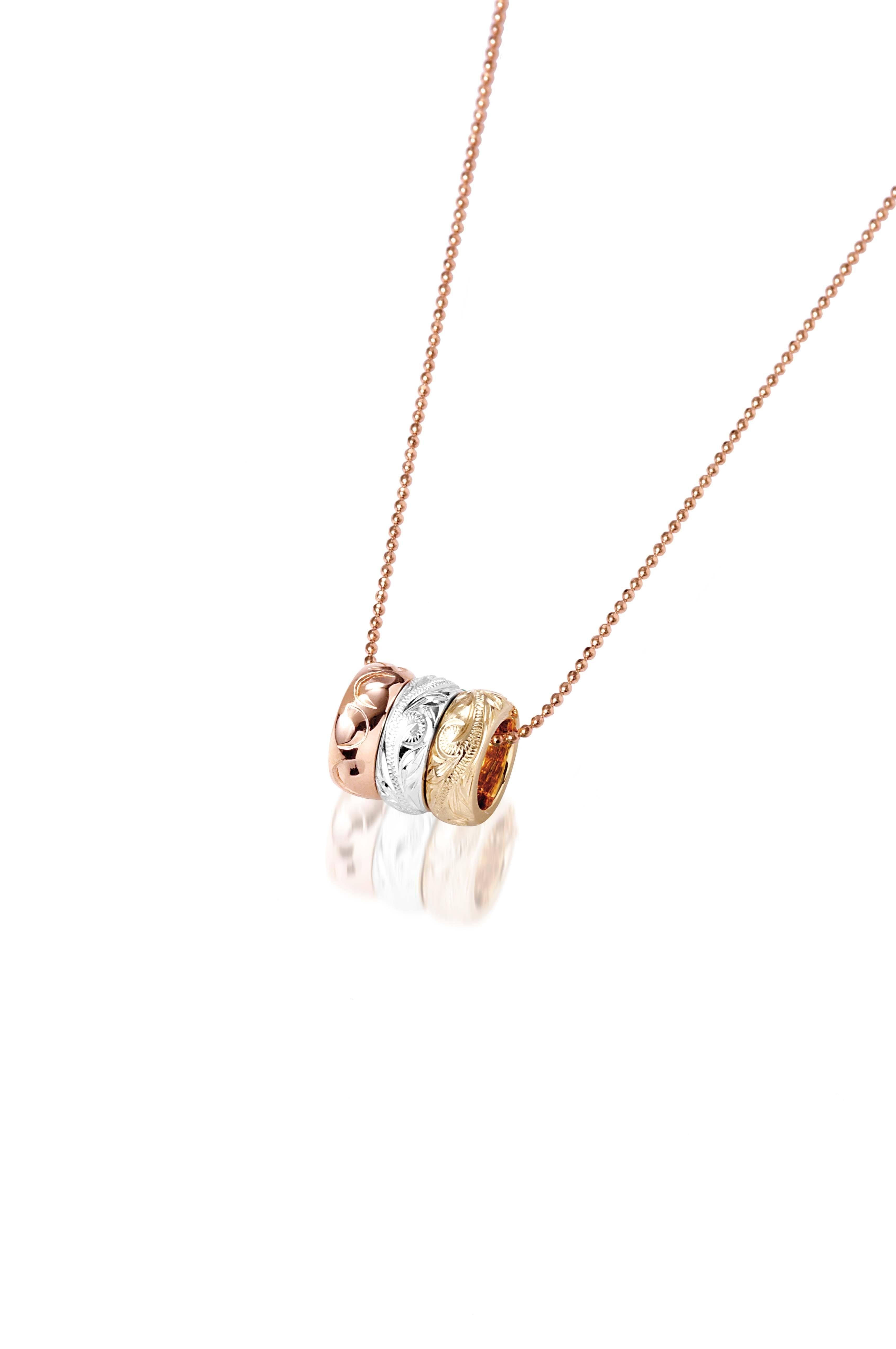 The picture shows a 14K rose, white, and yellow gold tricolor three ring pendant with hand engravings.