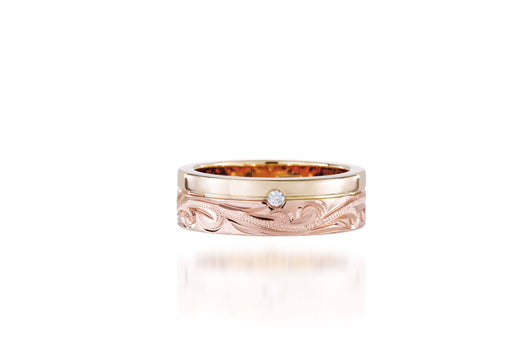 The picture shows a 14K yellow and rose gold two-tone pinched channel 6mm ring with a diamond and hand-engravings.