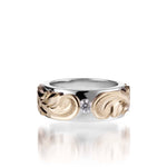 The picture shows a 14K white and yellow gold two-tone pinched 8 mm ring with hand-engravings and a diamond.