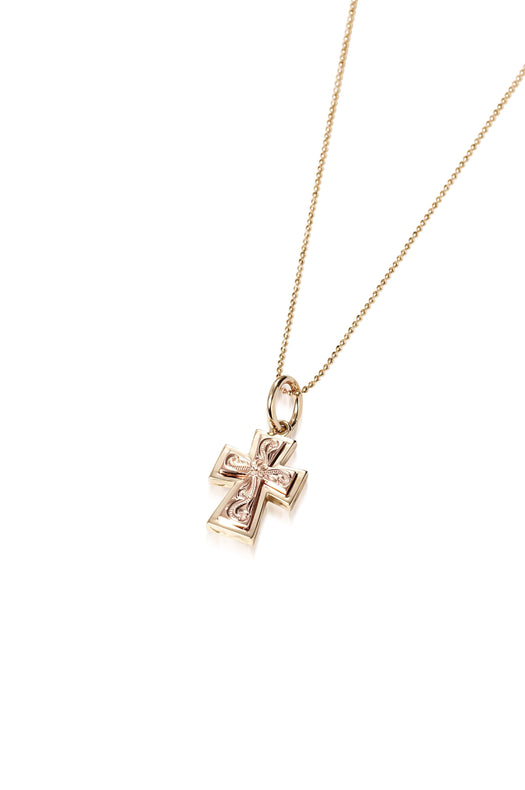 The picture shows a 14K yellow and rose gold two-tone cross pendant with hand engravings.