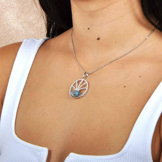 Sterling silver, white topaz, and abalone featured in a pendant with a unique design, the pendant is worn by a model. 