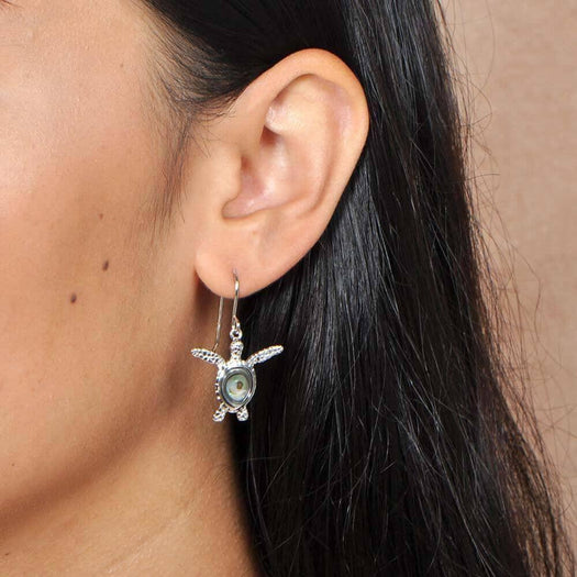 Sterling silver and abalone sea turtle hook earrings worn by a model. 