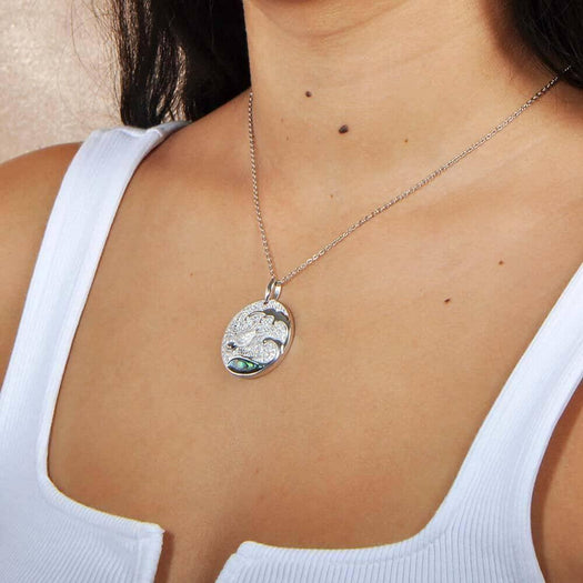 Sterling silver medallion pendant with a turtle swimming away from the abalone tides, worn by a model