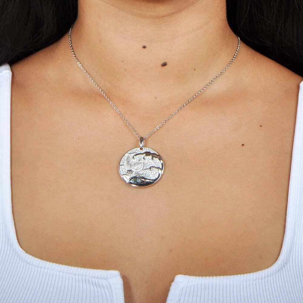 A model wearing a Sterling silver medallion pendant with a turtle swimming away from the abalone tides. 