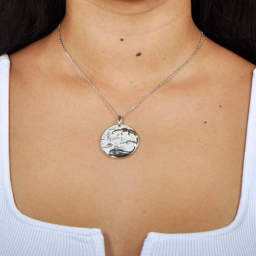A model wearing a Sterling silver medallion pendant with a turtle swimming away from the abalone tides. 