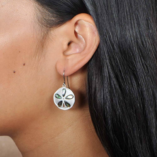 Sterling silver abalone earrings with a sand dollar design worn by a model. 