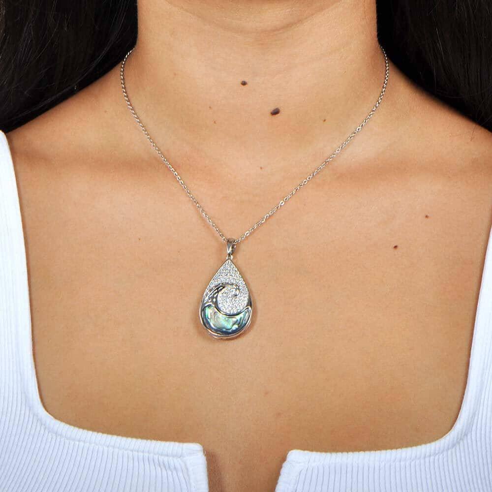 Sterling silver tear drop pendant with and abalone wave against the topaz sky worn by a model. 