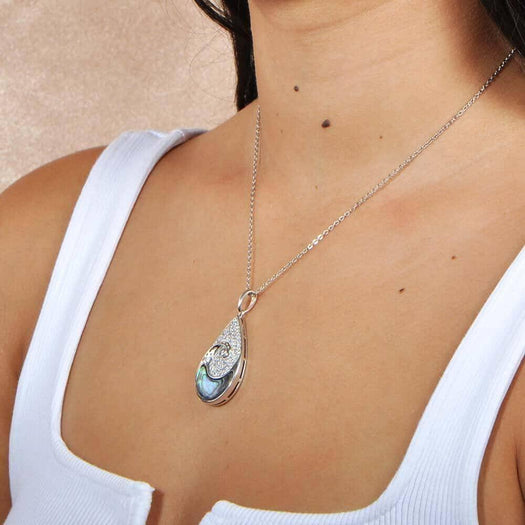 A model wearing a Sterling silver tear drop pendant with and abalone wave against the topaz sky. 