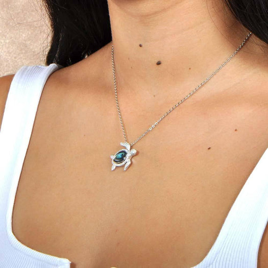 Sterling silver sea turtle pendant featuring Pave detail and an abalone shell. Worn by a model. 