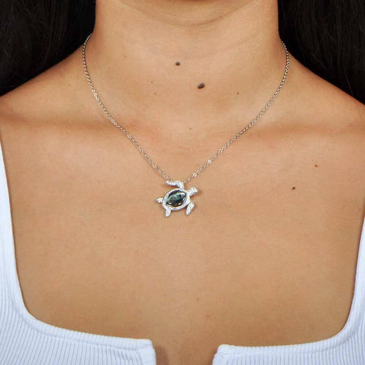 Sterling silver sea turtle pendant featuring Pave detail and an abalone shell. Worn by a model. 