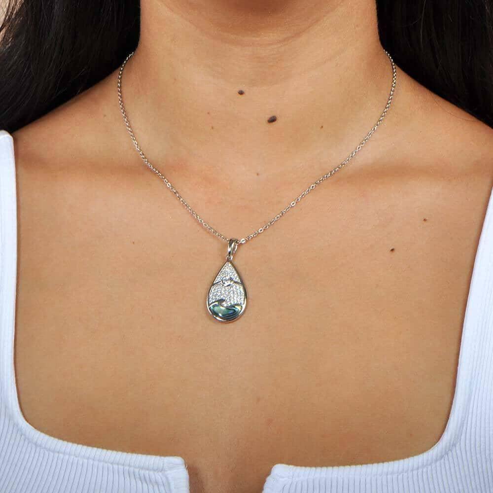 Abalone, white topaz, and sterling silver pendant featuring a sun and wave design, worn by a model. 