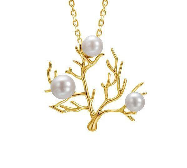 In this photo there is a large yellow gold coral pendant with three white pearls.