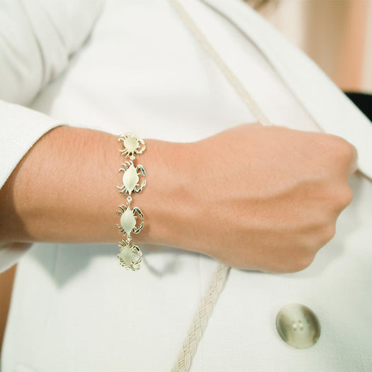 The picture shows a model wearing a  925 sterling silver yellow gold-plated blue crab bracelet.