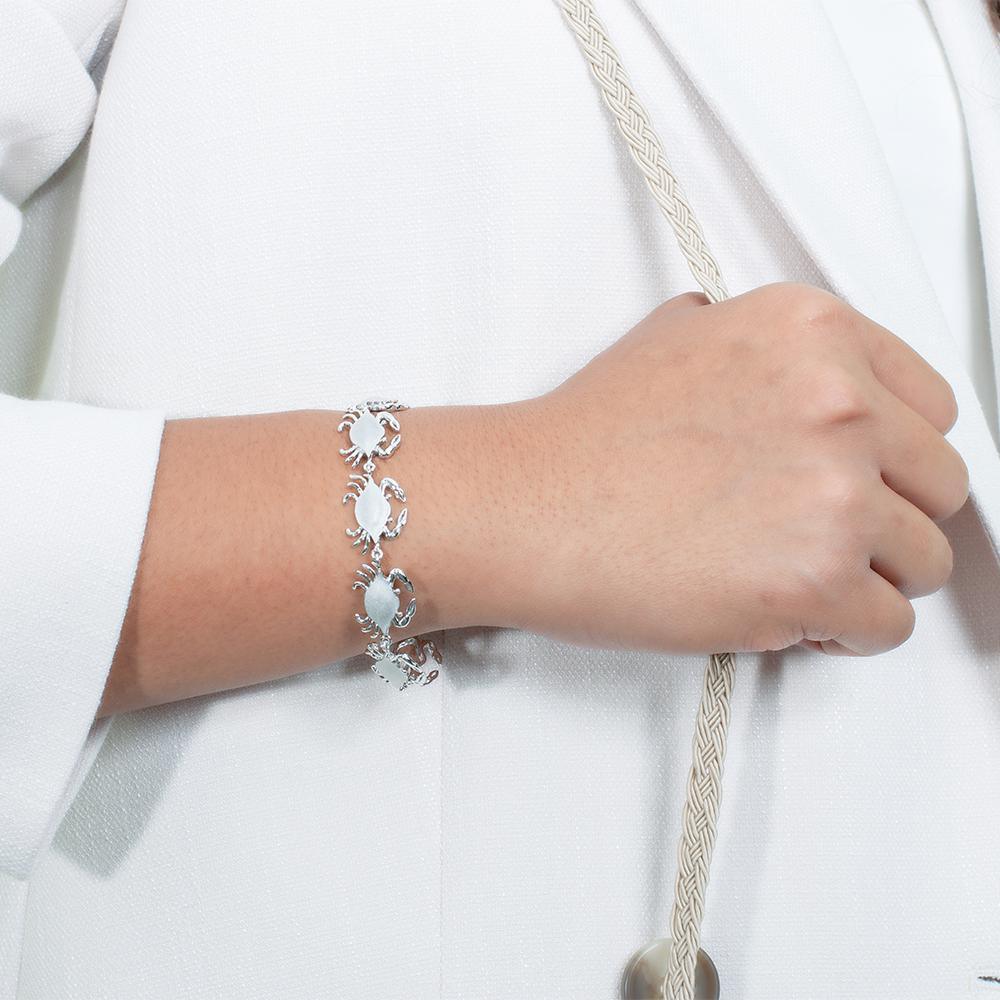 The picture shows a model wearing a 925 sterling silver white gold-plated blue crab bracelet.