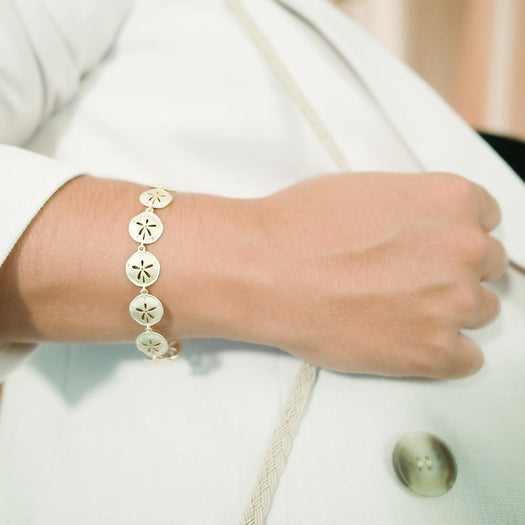 The picture shows a model wearing a 925 sterling silver yellow gold-plated sand dollar bracelet with topaz