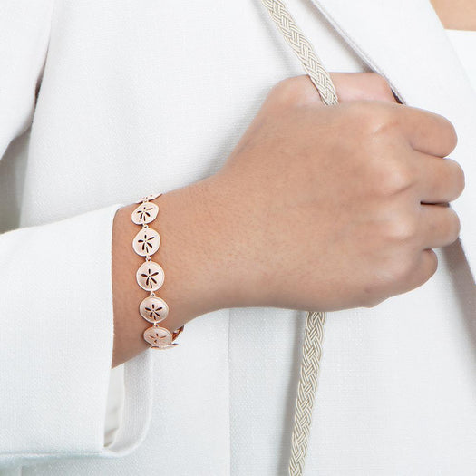 The picture shows a model wearing a 925 sterling silver rose gold-plated sand dollar bracelet with topaz