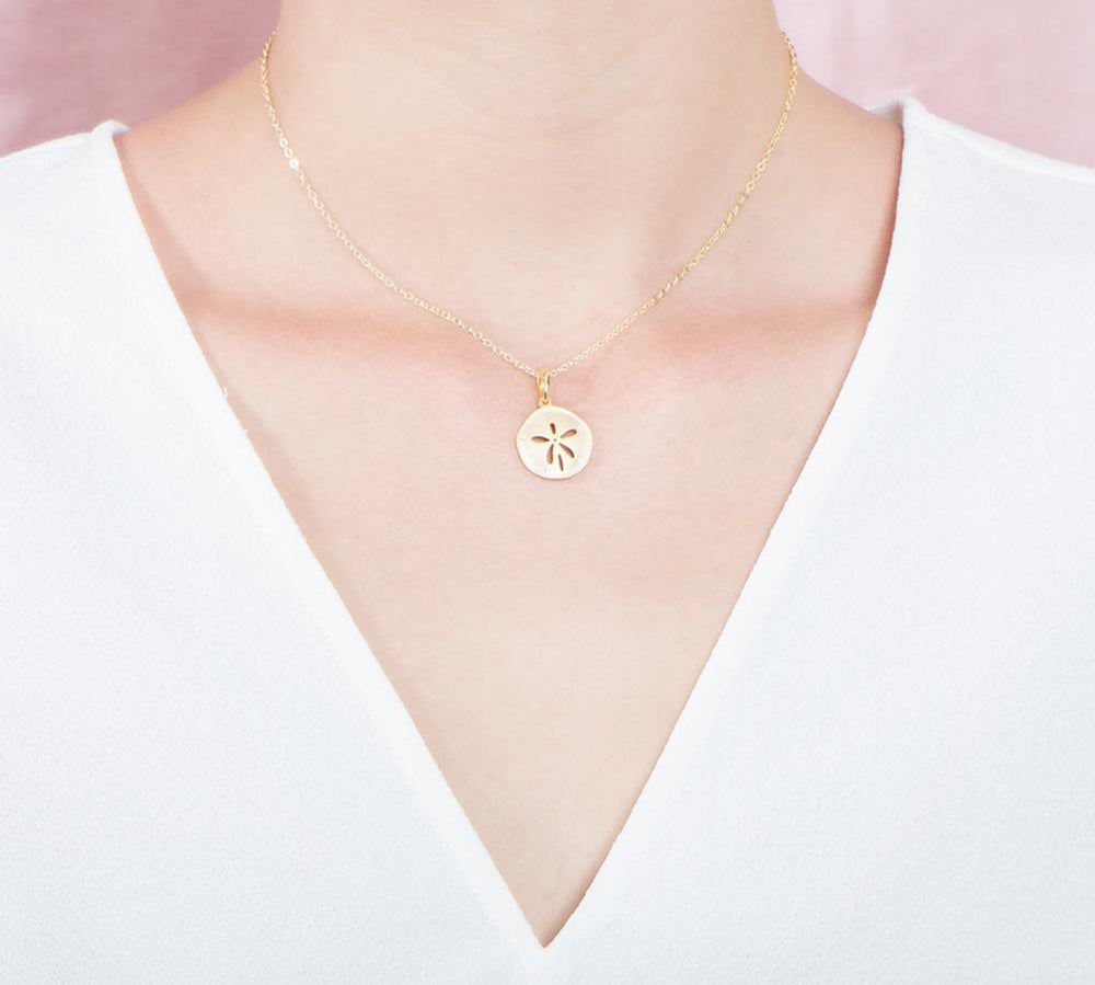 The picture shows a 925 sterling silver, yellow gold plated, sand dollar pendant with topaz.
