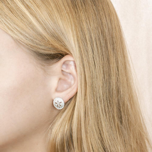 The picture shows a model wearnig a 925 sterling silver sand dollar stud earring with topaz.