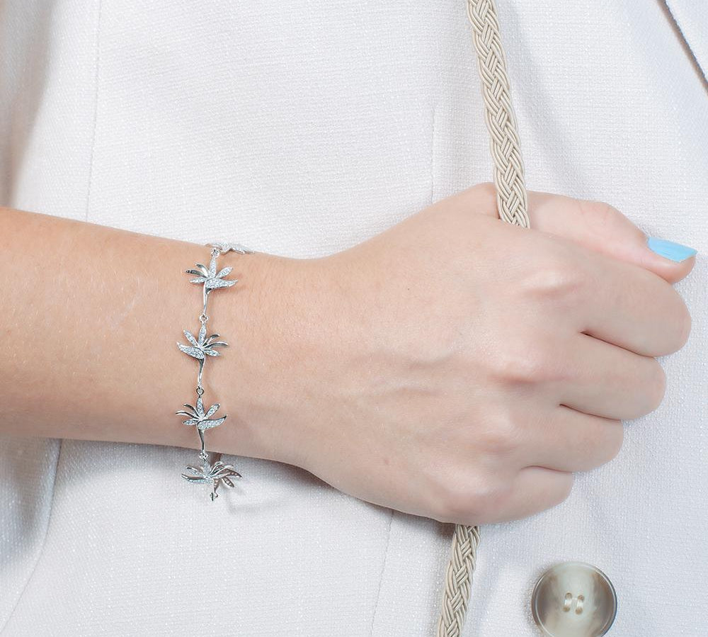 In this photo there is a model wearing a white gold plated bird of paradise bracelet with topaz gemstones.