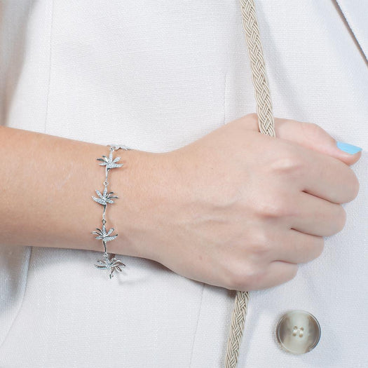 In this photo there is a model wearing a white gold plated bird of paradise bracelet with topaz gemstones.