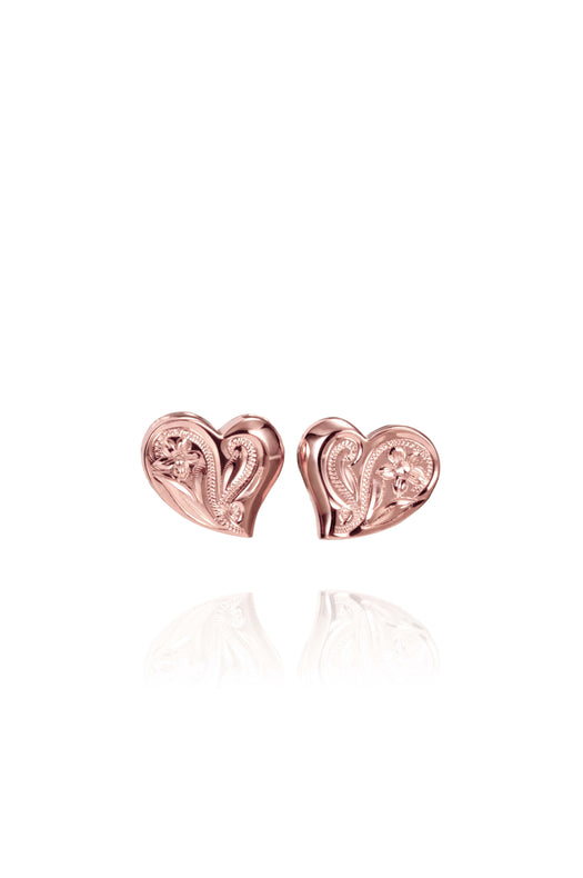 In this photo there is a pair of 14k rose gold heart stud earrings with plumeria flower engravings.