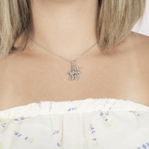 In this photo there is a model with blonde hair and a white shirt with purple flowers, wearing a sterling silver gecko pendant.