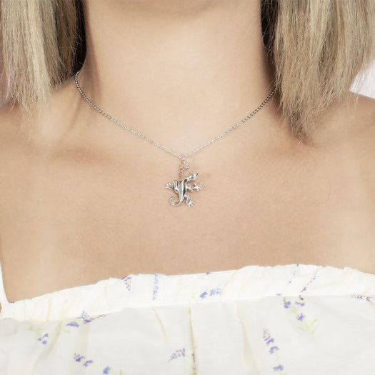In this photo there is a model with blonde hair and a white shirt with purple flowers, wearing a sterling silver gecko pendant.