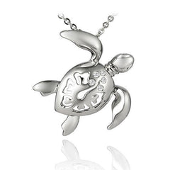 The picture shows a 925 sterling silver sea turtle pendant with hibiscus cut-out and topaz.