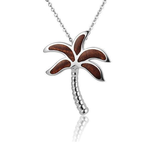 In this photo there is a small sterling silver and koa wood palm tree pendant.