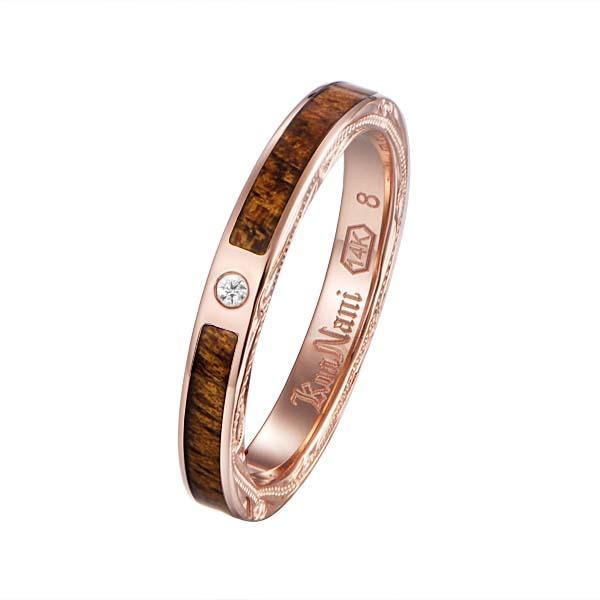 In this photo there is a rose gold koa wood ring with hand engravings of scrolls and one diamond.