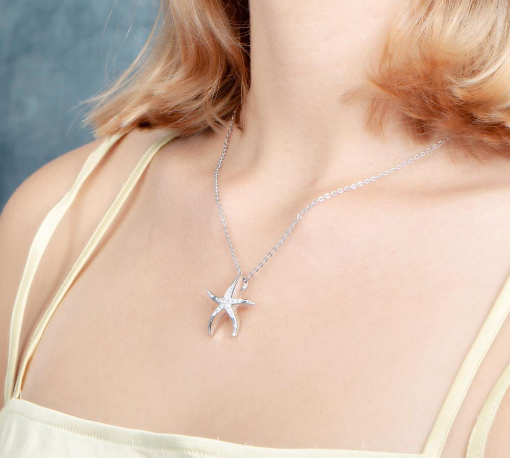 The picture shows a model wearing a 925 sterling silver starfish pendant with topaz.