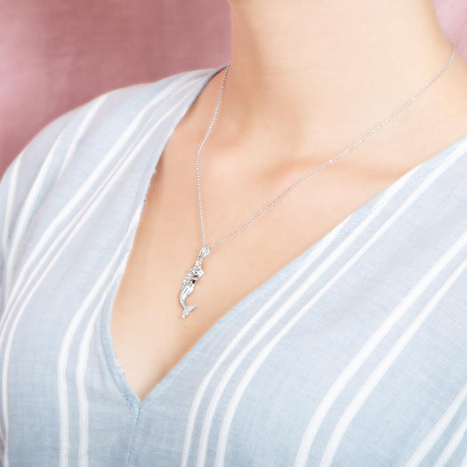 The picture shows a model wearing a 925 sterling silver mermaid pendant and a blue shirt with blue lines.